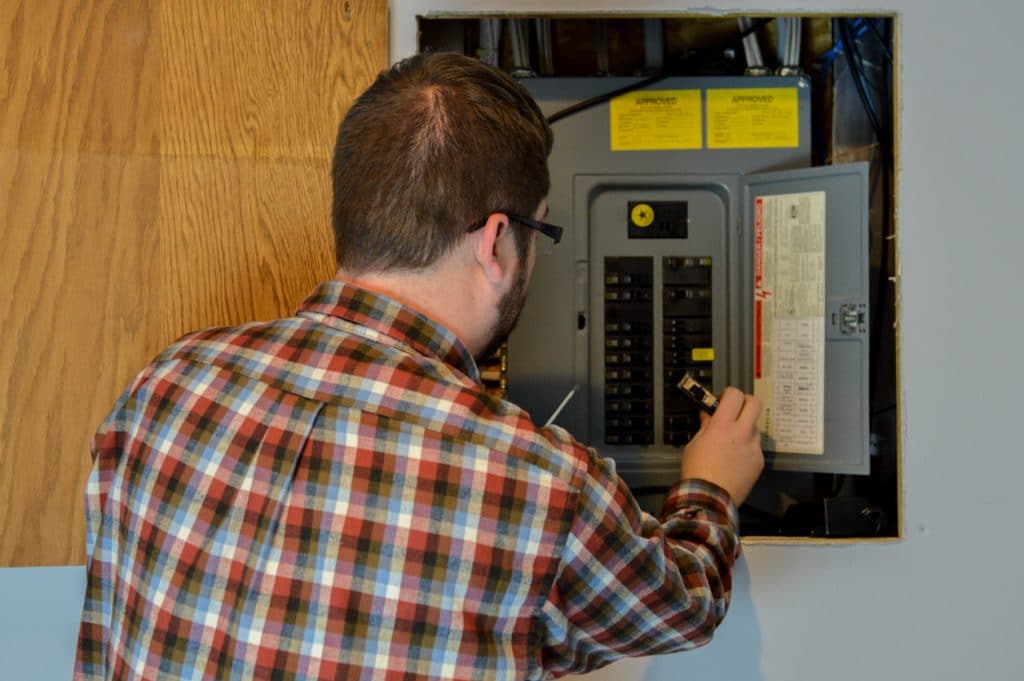 handyman/repairman inspecting an electric box/circuit breaker in a residential home