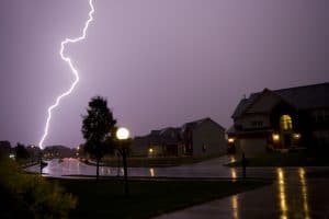 Lightening bolt striking in purple thunderstorm sky over neighborhood